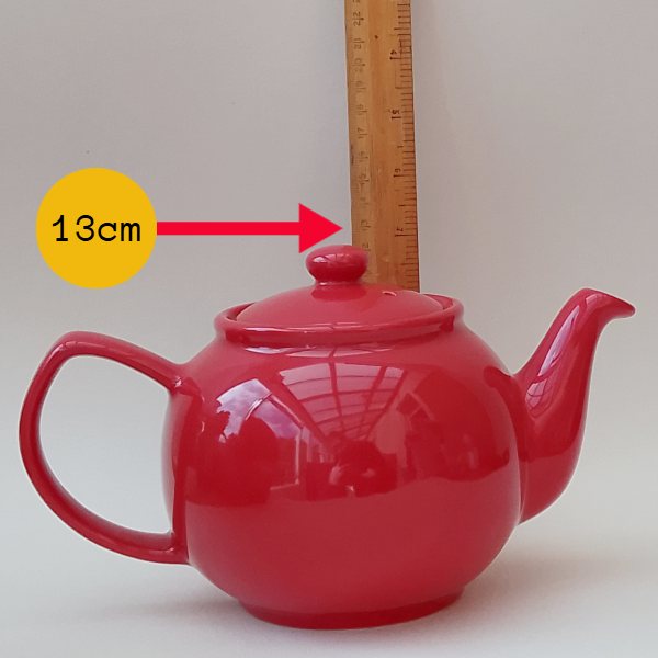 A teapot being measured with a ruler