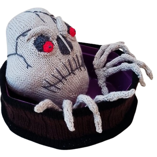 The Halloween Skull Quality Street Box Cover has bony hand bones that are knitted tubes