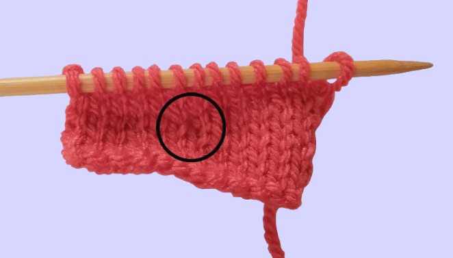 Wonky stitches circled to show where a backwards‑knitting error appears in the fabric